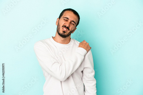 Young caucasian man isolated on blue background having a shoulder pain.