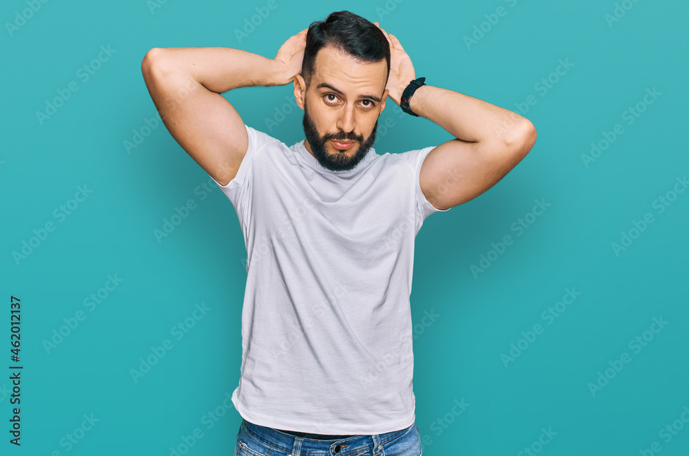 Young man with beard wearing casual white t shirt doing bunny ears gesture with hands palms looking cynical and skeptical. easter rabbit concept. Young man with beard wearing casual white t shirt doing bunny ears gesture with hands palms looking cynical and skeptical. easter rabbit concept.