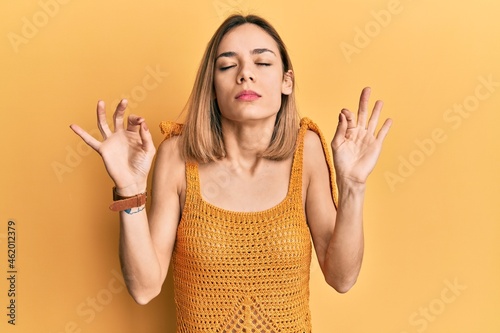 Young caucasian blonde woman wearing casual yellow t shirt relaxed and smiling with eyes closed doing meditation gesture with fingers. yoga concept.