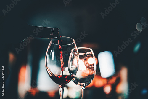 waiter pouring red wine into a glass in cafe or bar photo