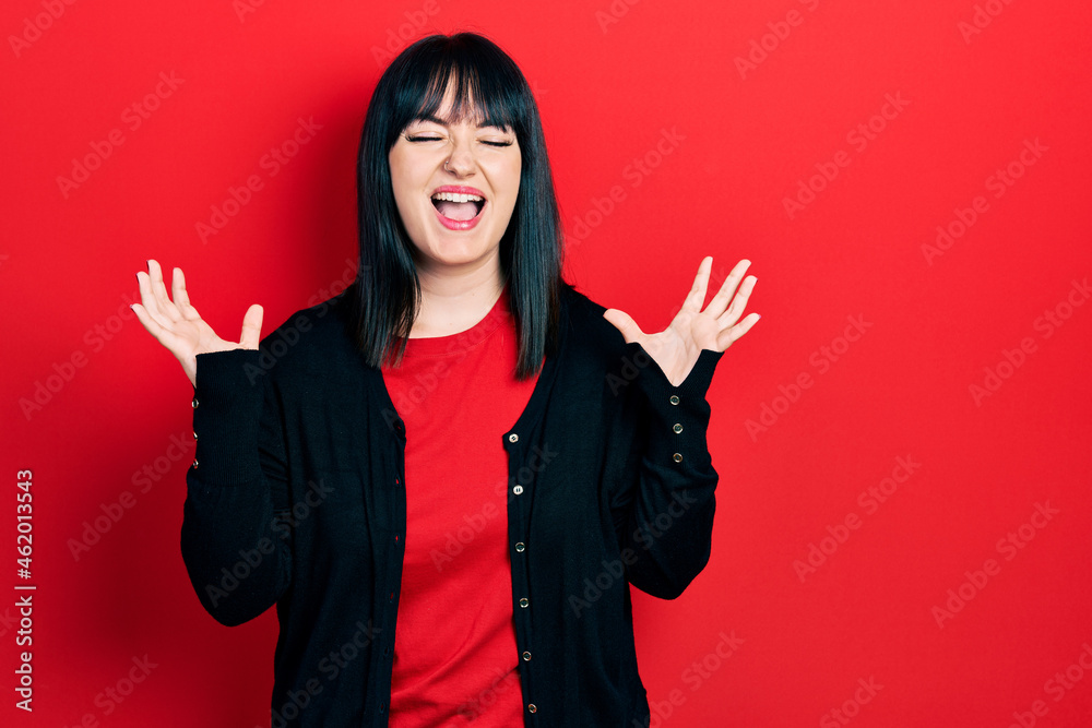 Young hispanic woman wearing casual clothes celebrating mad and crazy for success with arms raised and closed eyes screaming excited. winner concept Young hispanic woman wearing casual clothes celebrating mad and crazy for success with arms raised and closed eyes screaming excited. winner concept