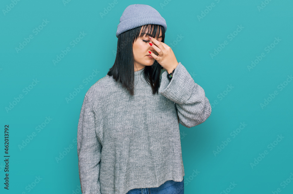 Young hispanic woman wearing cute wool cap tired rubbing nose and eyes feeling fatigue and headache. stress and frustration concept. Young hispanic woman wearing cute wool cap tired rubbing nose and eyes feeling fatigue and headache. stress and frustration concept.