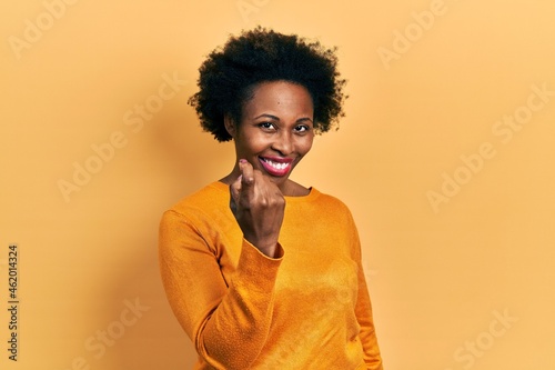 Young african american woman wearing casual clothes beckoning come here gesture with hand inviting welcoming happy and smiling