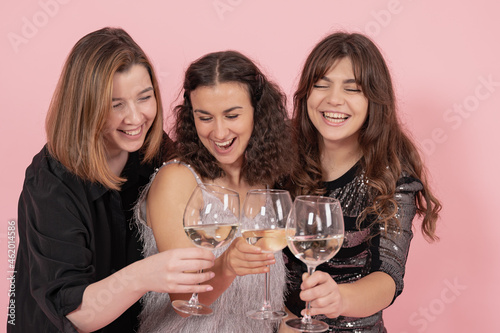 The company of girls with glasses of champagne on a pink background.