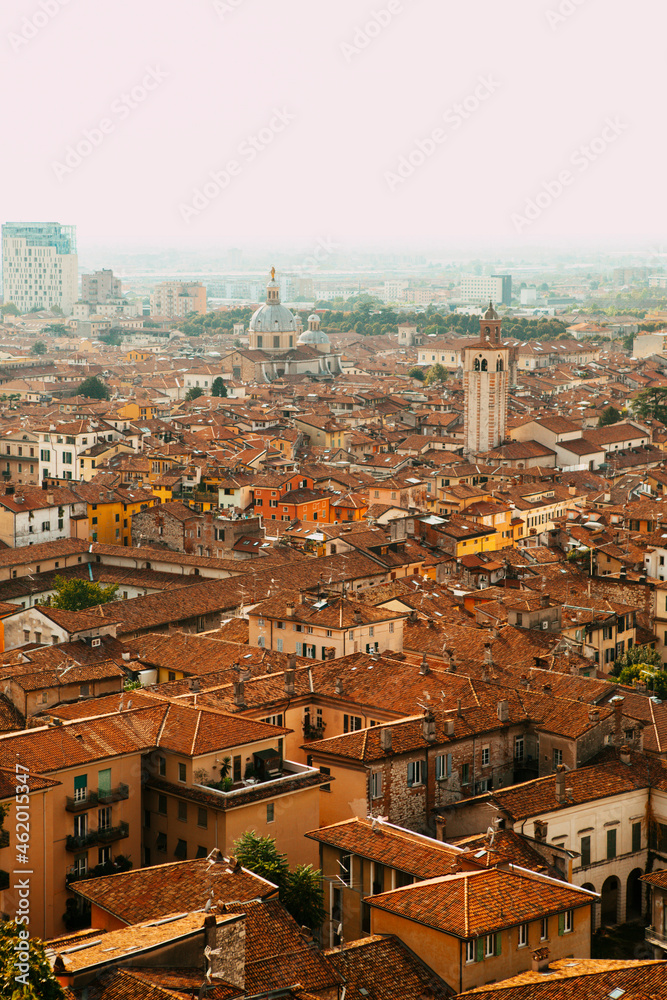 Aerial view of the historical center of Brescia (Lombardy, Italy) with red tile roofs, chimneys, cathedral's domes and tall white brick old towers. Traditional European medieval architecture.