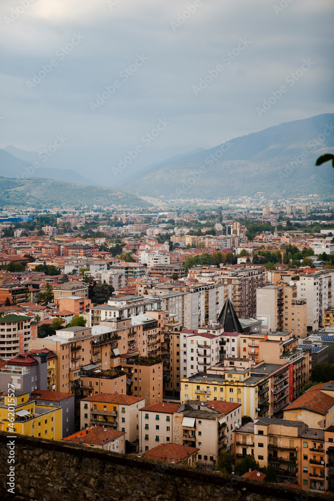 Aerial view of the mountains and  the modern centre of Brescia (Lombardy, Italy) with tiled red roofs, chimneys, cathedral's domes and tall white brick old towers. Traditional European architecture.