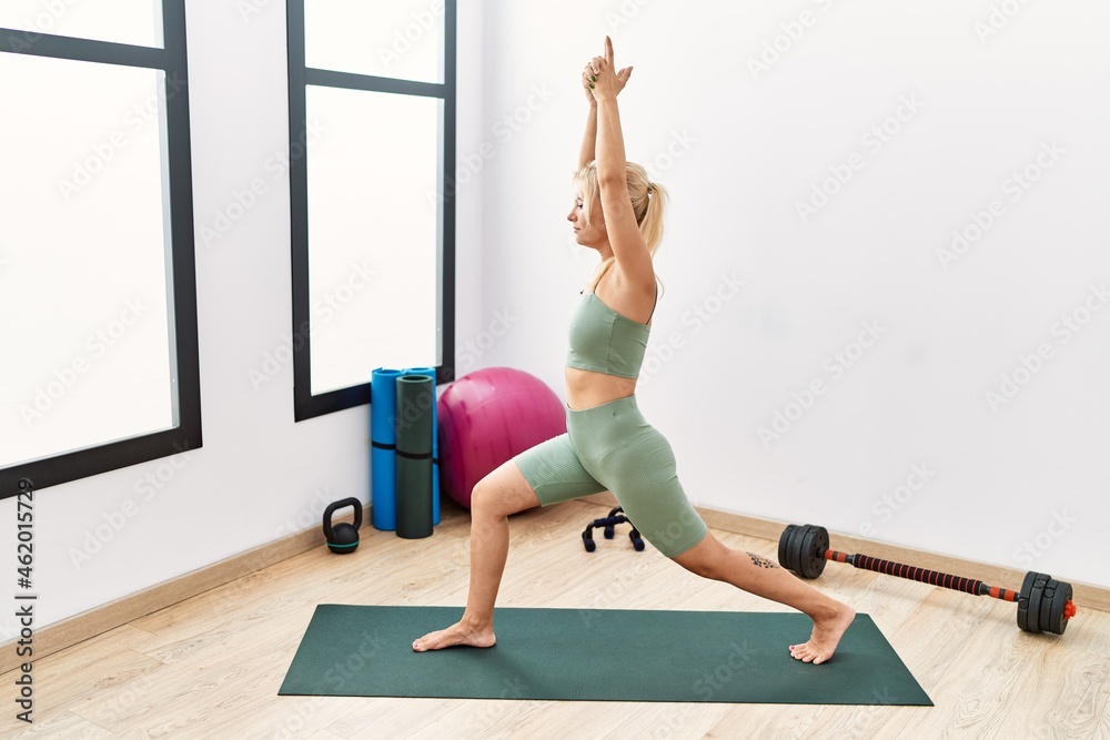 Naklejka premium Young blonde girl smiling happy training yoga at sport center.