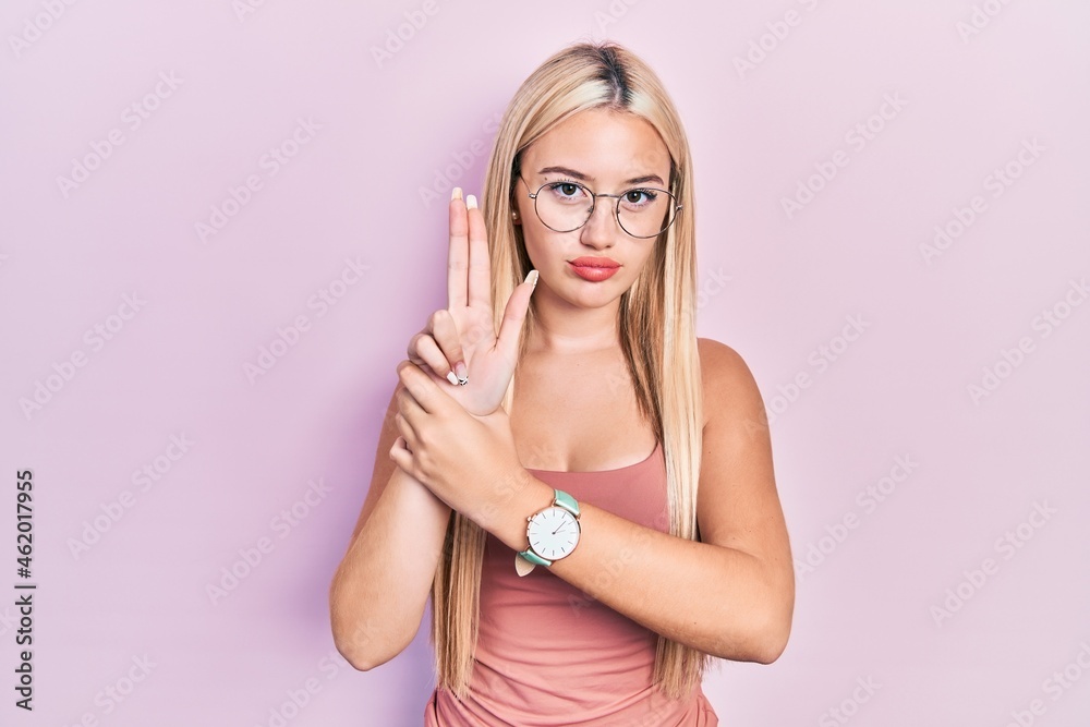 Young blonde girl wearing casual clothes holding symbolic gun with hand gesture, playing killing shooting weapons, angry face Young blonde girl wearing casual clothes holding symbolic gun with hand gesture, playing killing shooting weapons, angry face