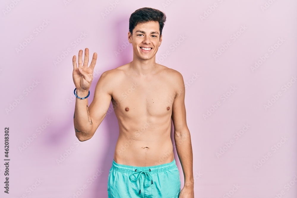 Young hispanic man wearing swimwear shirtless showing and pointing up with fingers number four while smiling confident and happy. Young hispanic man wearing swimwear shirtless showing and pointing up with fingers number four while smiling confident and happy.