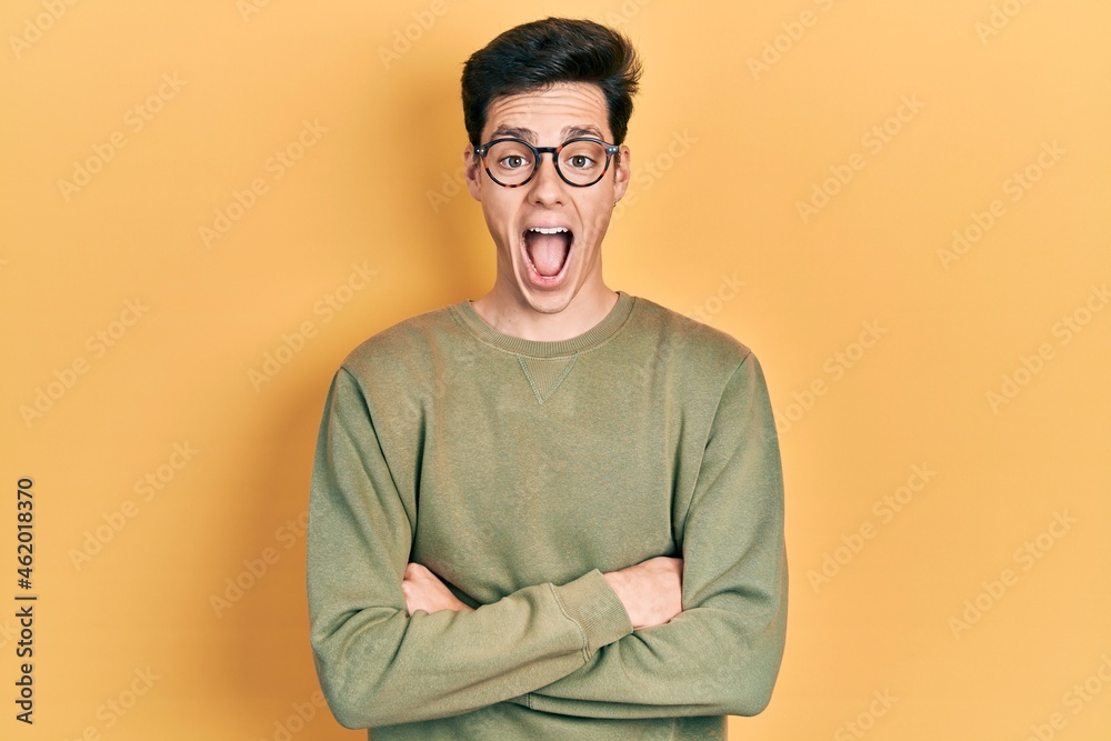 Young hispanic man with arms crossed gesture celebrating crazy and amazed for success with open eyes screaming excited. Young hispanic man with arms crossed gesture celebrating crazy and amazed for success with open eyes screaming excited.