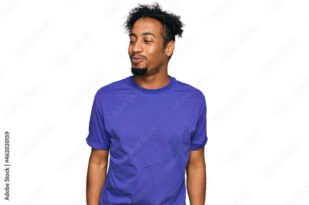Young african american man with beard wearing casual purple t shirt smiling looking to the side and staring away thinking. Young african american man with beard wearing casual purple t shirt smiling looking to the side and staring away thinking.