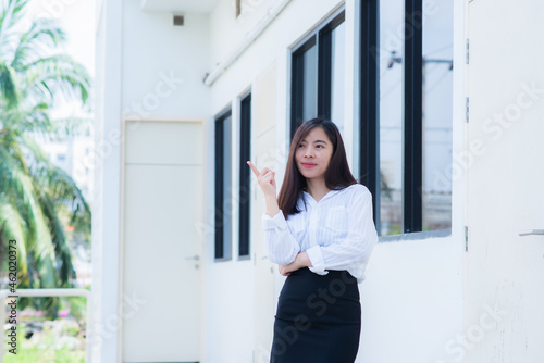 attractive adult business woman asian girl finger point up with happy and smile front of her office.