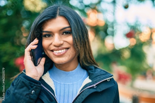 Young hispanic woman speaking on the phone outdoor by christmas decorations