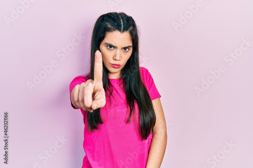 Young hispanic girl wearing casual pink t shirt pointing with finger up and angry expression  showing no gesture