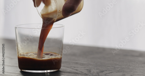 pour espresso in tumbler glass on black aok table photo