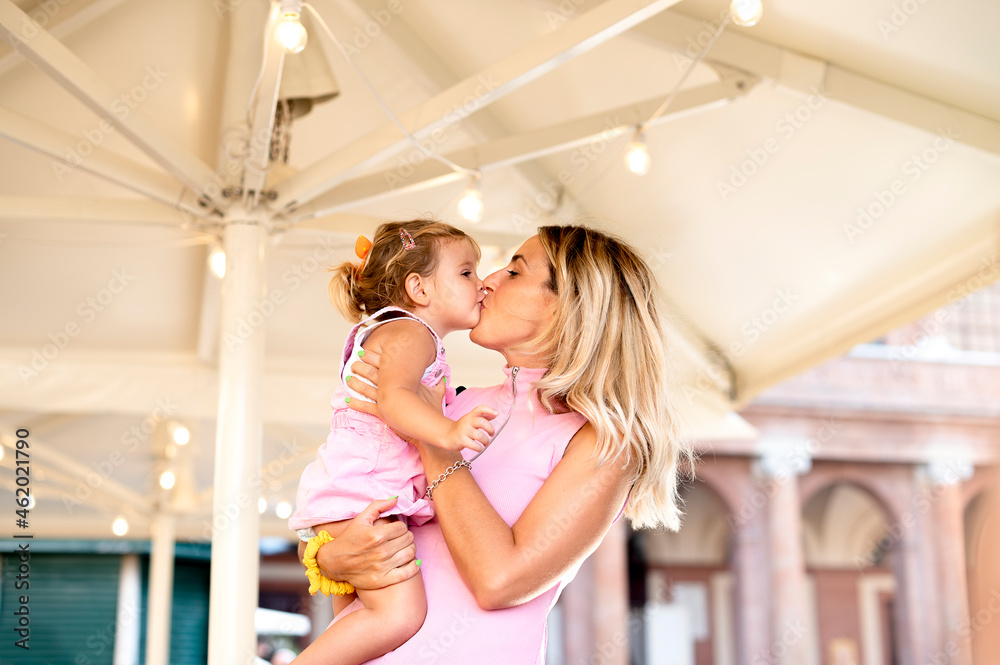 Happy loving family - Beautiful blond mother hugging and  kissing her sweet daughter on street in the trip - Family, motherhood and people concept