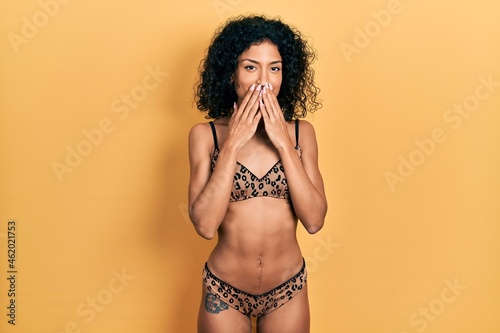 Schilderij op canvas Young latin girl wearing bikini laughing and embarrassed giggle covering mouth w
