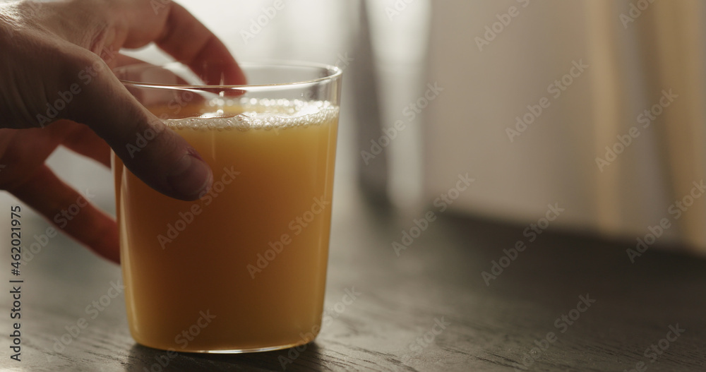 man hand take orange juice in tumbler glass from black wood table with copy space man hand take orange juice in tumbler glass from black wood table with copy space