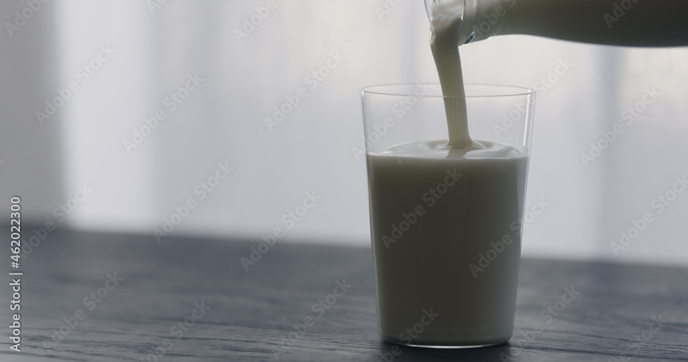 pour organic yogurt in tumbler glass on black wood table with copy space pour organic yogurt in tumbler glass on black wood table with copy space