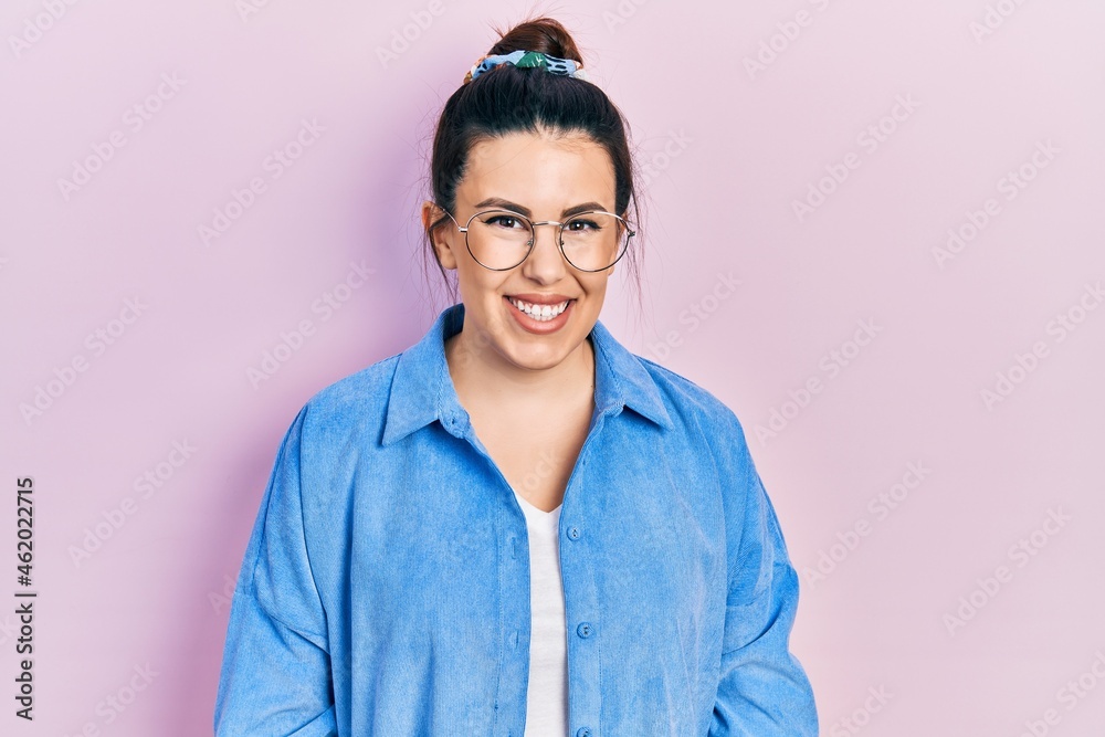 Young hispanic woman wearing casual clothes and glasses looking positive and happy standing and smiling with a confident smile showing teeth Young hispanic woman wearing casual clothes and glasses looking positive and happy standing and smiling with a confident smile showing teeth