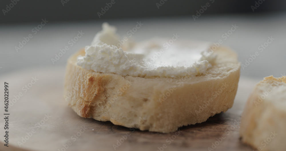 cream cheese on fresh baguette slice on olive board closeup cream cheese on fresh baguette slice on olive board closeup