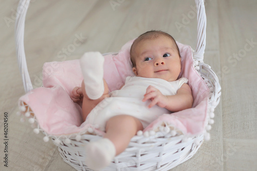 Smiling baby is lying in a white basket.concept of a healthy child