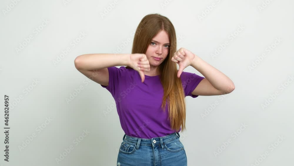 Teenager girl doing bad signal over isolated background Teenager girl doing bad signal over isolated background