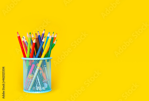 Pencils. Colored pencils in a glass on a yellow background