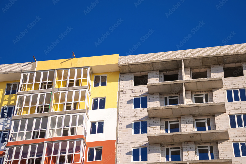 Building a new residential building. Urban real estate concept. Construction site and brick walls of building under construction against blue sky background