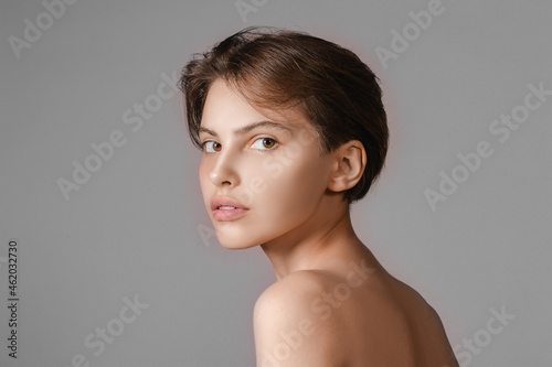 Beautiful young woman without makeup on gray background