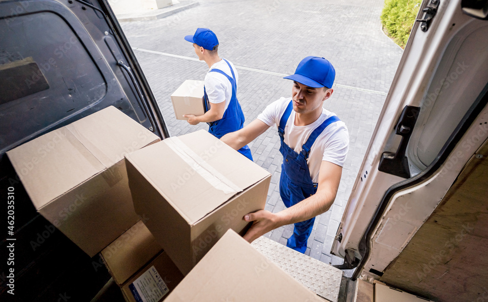 Two removal company workers unloading boxes from minibus Two removal company workers unloading boxes from minibus