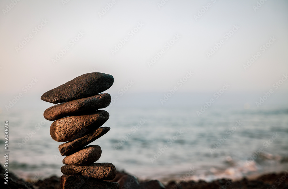 Fototapeta premium Tower of rocks on beach during sunrise