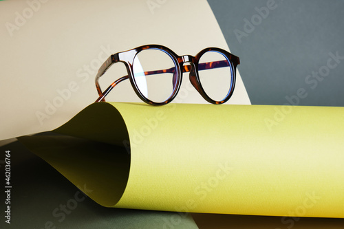 glasses on rolled paper, geometric background, green colors photo