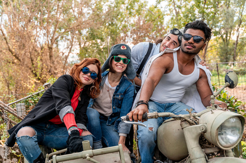 group of best friends together have fun riding a vintage motorcycle with sidecar
