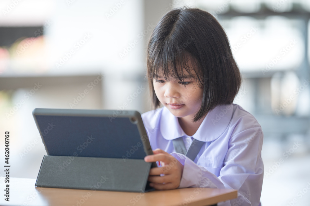 Asian child student studying and writing on a digital tablet outdoor education school. Back to School Concept Stock Photo Asian child student studying and writing on a digital tablet outdoor education school. Back to School Concept Stock Photo