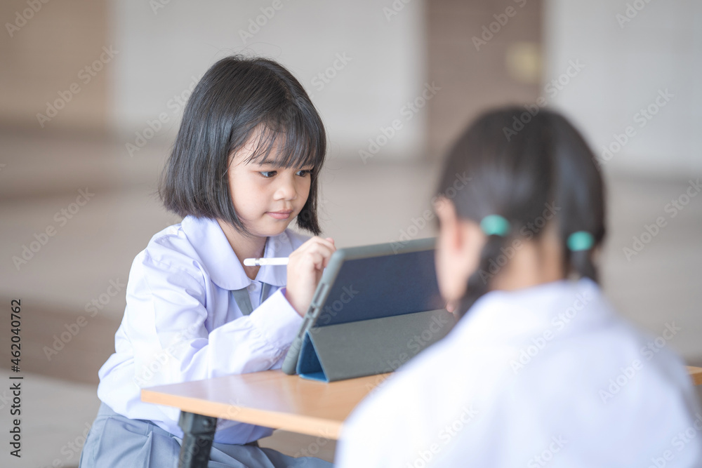 Asian child student studying and writing on a digital tablet outdoor education school. Back to School Concept Stock Photo Asian child student studying and writing on a digital tablet outdoor education school. Back to School Concept Stock Photo