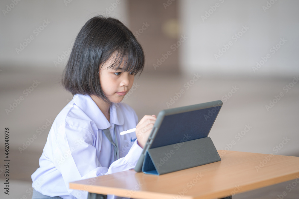 Asian child student studying and writing on a digital tablet outdoor education school. Back to School Concept Stock Photo Asian child student studying and writing on a digital tablet outdoor education school. Back to School Concept Stock Photo