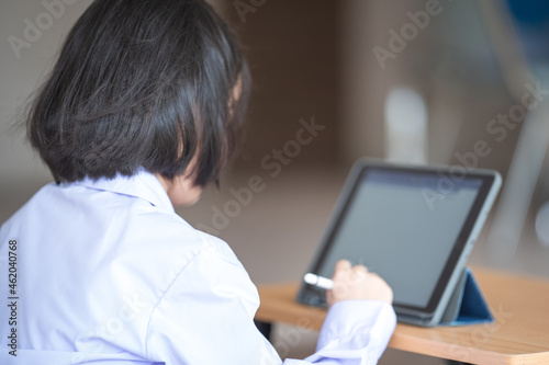 Asian child student studying and writing on a digital tablet outdoor education school. Back to School Concept Stock Photo