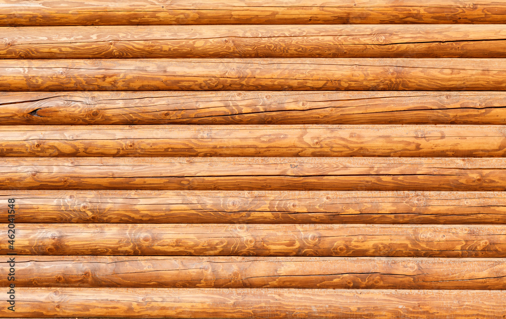 Modern, new, clean log wall made of round logs covered with stain Modern, new, clean log wall made of round logs covered with stain
