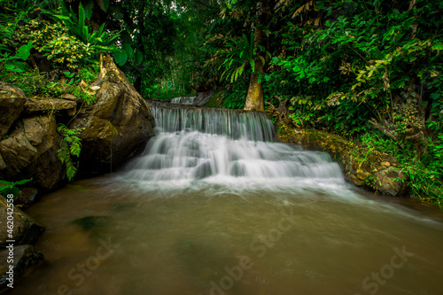 The natural background of waterfalls that blur the flow of water, with various tree species surrounded and boulders of various sizes, the beauty of the ecosystem and the jungles of forests.