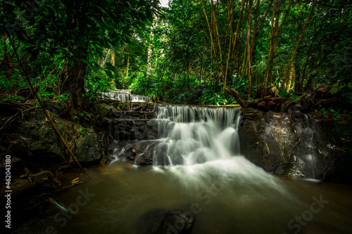 The natural background of waterfalls that blur the flow of water, with various tree species surrounded and boulders of various sizes, the beauty of the ecosystem and the jungles of forests.