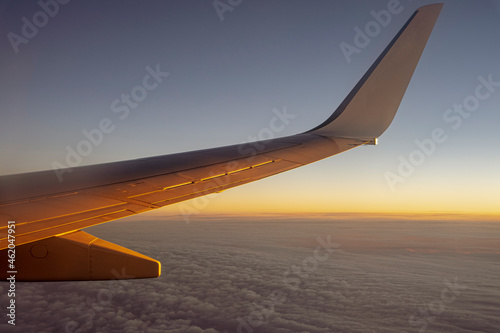 Lot samolotu przy wschodzie słońca, widok na skrzydło samolotu. 