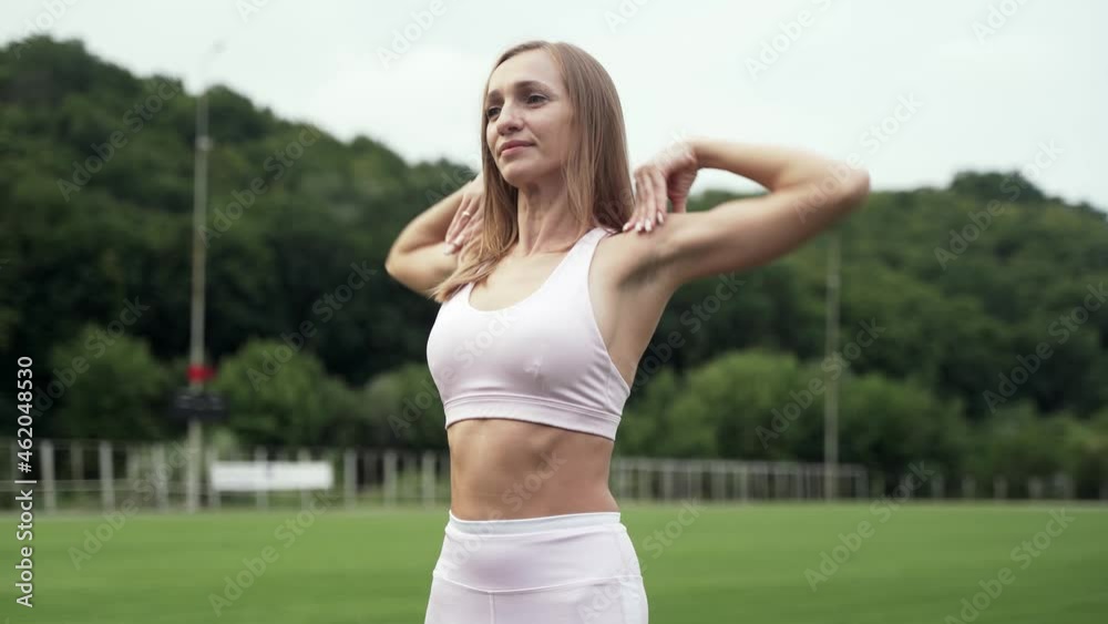 Woman kneading her shoulders doing swings with her hands, outdoors Woman kneading her shoulders doing swings with her hands, outdoors