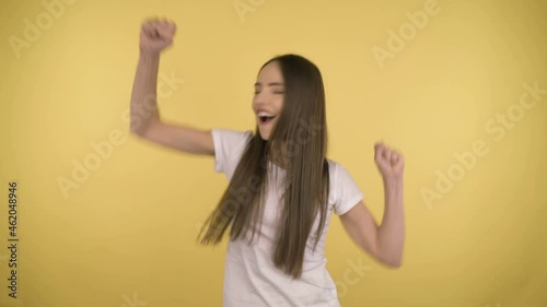 Funny attractive woman 35 years old middle age on yellow background in studio in profile. Woman having fun dancing on yellow background isolated