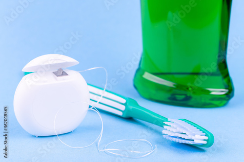 Tooth care and oral hygiene products. Dental floss, toothbrush and mouthwash on blue background