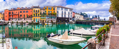 Idyllic lake scenery - tranquil beautiful village (town) Peschiera del Garda with fishing boats and colorful houses. Lago di Garda, northern Italy