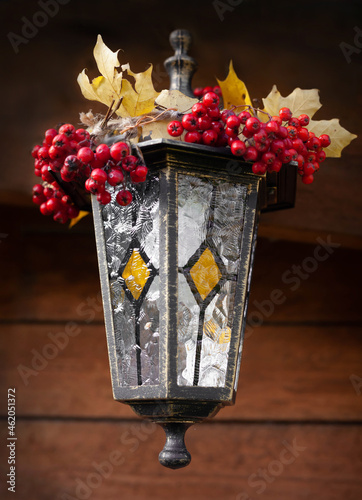 vintage handmade lantern with painting and garland  of maple leaves and rowen berries photo