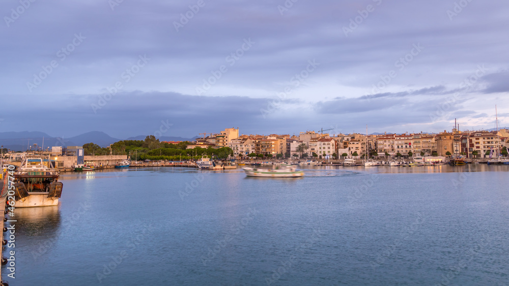 View of Fishing Boat Arriving to Dock in Small Spanish Town With Dense Clouds in the Sky