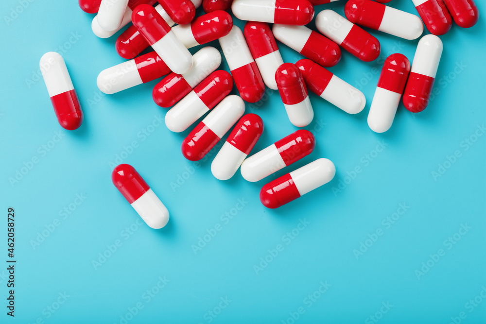 A handful of Red and white pill capsules on a blue background. Free space Top view A handful of Red and white pill capsules on a blue background. Free space Top view