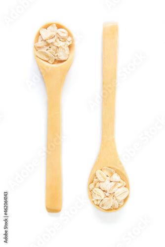 Top view of dry rolled oatmeal in wooden spoon isolated on white background.
